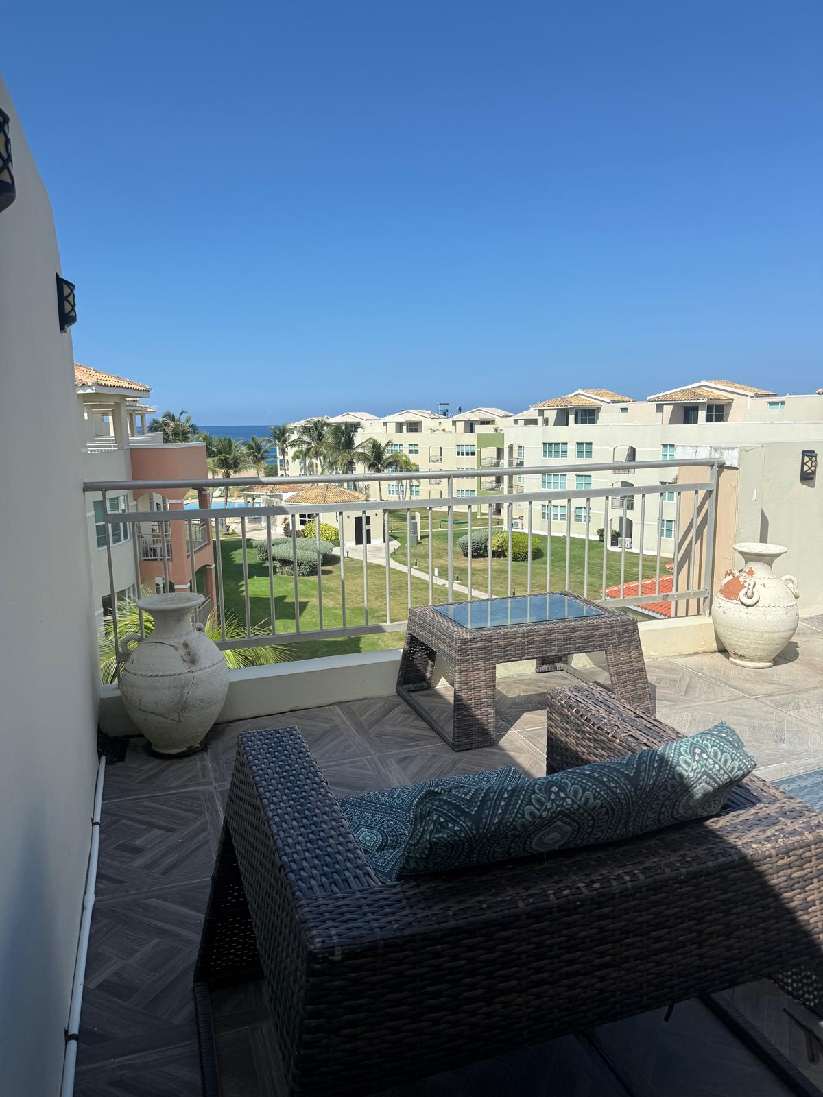 Studio terrace with wicker seating and ocean views over Haudimar gardens